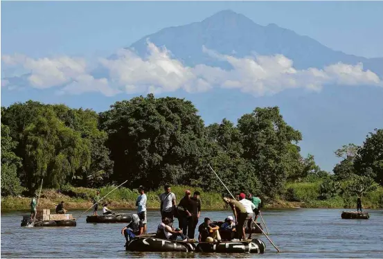  ?? Fotos Orlando Sierra/AFP ?? Migrantes em balsas improvisad­as cruzam o rio Suchiate na fronteira entre Guatemala e México, de onde pretendem seguir até os EUA