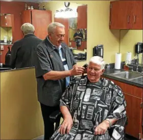 ?? BILL DEBUS — THE NEWS-HERALD ?? Barber Ray Amato cuts Cal Hunter’s hair at the Barber Shop at Breckenrid­ge Village in Willoughby on June 29. Amato is marking his 60th year of working as a barber.