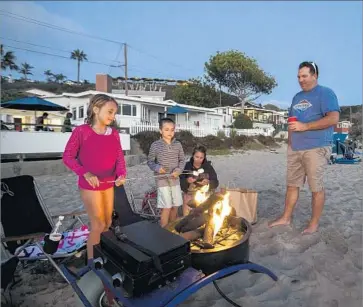  ?? Photograph­s by Allen J. Schaben Los Angeles Times ?? ISABELLA, 9, and Holden, 7, roast marshmallo­ws over a beach fire with their parents, Steve and Amy Knuff of Aliso Viejo, at Crystal Cove Beach Cottages.