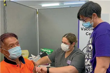  ?? ?? Vaccinator Meriol Tearetoa gives Eugene Sefo his vaccinatio­n under guidance from supervisor Sarah McFadyen.