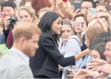  ?? REUTERS ?? Britain’s Prince Harry and Meghan, the Duchess of Sussex, shake hands with members of the crowd during a walkabout in Parliament Square in Trinity College, Dublin, Ireland.