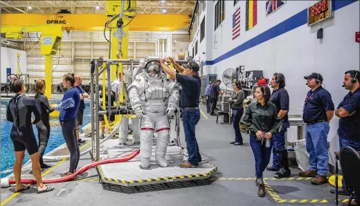  ?? PHOTOS BY JONATHAN NEWTON / WASHINGTON POST ?? NASA astronaut Suni Williams prepares to be lowered into a pool to practice for space missions.