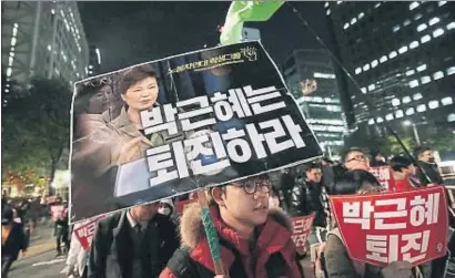  ?? AHN YOUNG-JOON / AP ?? Manifestan­tes muestran carteles con las imágenes de Park Geun Hye y su amiga Choi Sun Sil