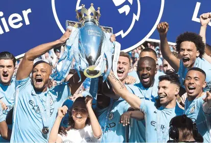  ??  ?? Manchester City captain Vincent Kompany (second left) and striker Sergio Aguero lift up the English Premier League trophy on the pitch after their EPL match against Huddersfie­ld Town at the Etihad Stadium in Manchester, northwest England, yesterday....