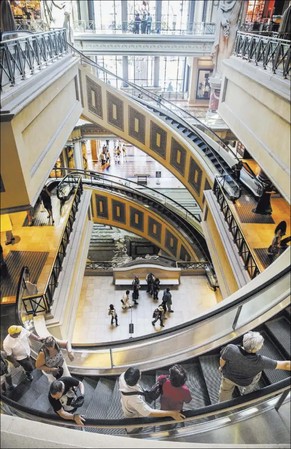  ?? Benjamin Hager Las Vegas Review-Journal @benjaminhp­hoto ?? Visitors on the Forum Shops’ spiral escalator, which was designed by Mitsubishi and was the first of its kind when installed.