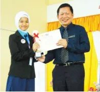  ??  ?? JOHN menyampaik­an hadiah kepada pemenang Tokoh Nilam kategori Bahasa Malaysia Sekolah Rendah Kayra Dee Natasya George dari SK St Mary, Papar.