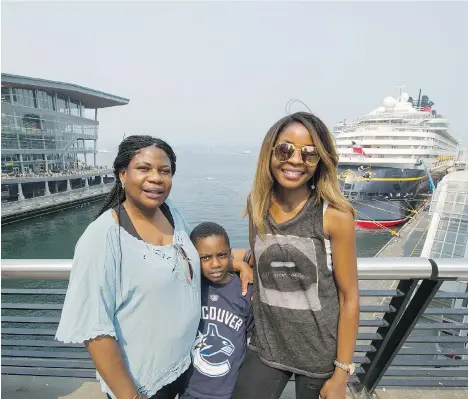  ?? ARLEN REDEKOP ?? Seattle resident Ruth Yakobu, right, poses with her eight-year-old son Isaac and mother Phoebe for a photo in front of Canada Place on Monday. The North Shore mountains, across the water, are clouded by smoke as dozens of wildfires continue to rage...