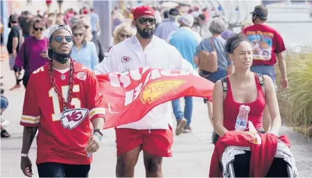  ?? CHARLIE RIEDEL/AP ?? People walk near Super Bowl activities Friday in Tampa. As the pandemic rages on with virus variants emerging, health officials are concerned that Super Bowl parties and get-togethers could become supersprea­der events.