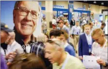  ?? THE ASSOCIATED PRESS ?? An image of Warren Buffett is seen Friday above Berkshire Hathaway shareholde­rs on the exhibit floor at the CenturyLin­k Center in Omaha, Neb., where Berkshire brands display their products and services.