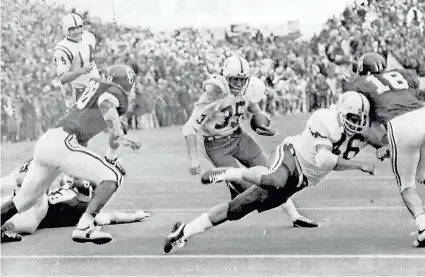  ?? TULSA WORLD VIA AP ?? Nebraska halfback Jeff Kinney (35) gets a block from fullback Maury Damkroger (46) on a fourth-down conversion during the 1971 game at OU. Kinney scored four touchdowns in the Huskers’ 35-31 win in the Game of the Century.