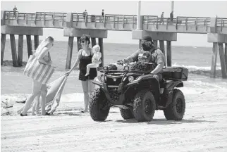  ?? JOE CAVARETTA/SOUTH FLORIDA SUN SENTINEL ?? A Broward deputy warns Pompano Beach visitors to avoid placing towels on the sand or sunbathing Tuesday. County beaches are open but with social distancing and activity restrictio­ns.