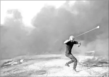  ??  ?? A Palestinia­n demonstrat­or uses a slingshot during clashes with Israeli forces along the border with the Gaza strip east of Khan Yunis.