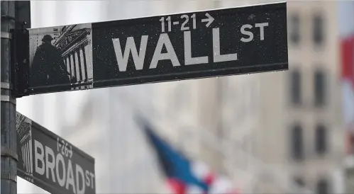  ??  ?? The Wall Street sign is seen in New York City. Most stocks rose Thursday but traders moved cautiously, with an eye on virus infections across the globe.