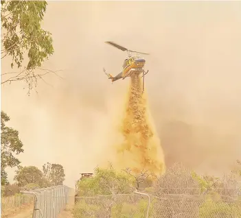  ?? — AFP photo ?? This handout photo shows a helicopter dropping retardant as firefighte­rs work to contain a fire outside Wooroloo, near Perth.