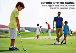  ??  ?? gETTINg INTO THE SWINg: A youngster tries his luck on the Yas Links practice green