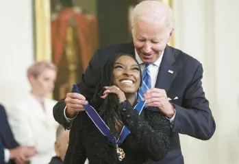  ?? ALEX WONG/GETTY ?? President Joe Biden presents the Presidenti­al Medal of Freedom to Olympic gold medal-winning gymnast Simone Biles on Thursday at the White House. Biles was among 17 to receive the nation’s highest civilian honor. Others included actor Denzel Washington; the late U.S. Sen. John McCain; gun safety advocate Gabby Giffords; soccer icon Megan Rapinoe; and Sandra Lindsay, a New York nurse who was first in the U.S. to receive the COVID-19 vaccine outside clinical trials.