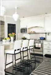  ?? LAURA HULL/BETSY BURNHAM VIA AP ?? Although pendant lights were once popular, designers today tend to choose more substantia­l overhead lighting above kitchen islands and select fixtures that express the homeowners’ style.