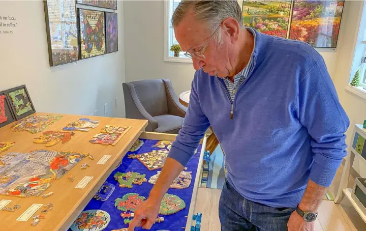  ?? Art Petrosemol­o photos ?? Stave Puzzles’ founder Steve Richardson examines puzzles from the company’s history, dating back to 1974.