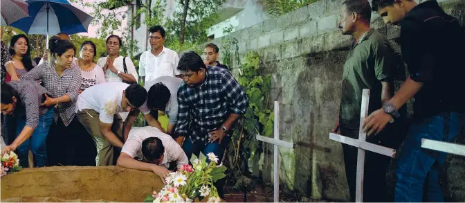  ??  ?? Il lutto
I parenti seppellisc­ono i loro cari morti nell’attacco alla chiesa di San Sebastiano a Negombo, a nord della capitale Colombo. Nell’attentato alla chiesa sono morte oltre 100 persone. Oggi è stato proclamato un giorno di lutto nazionale (Foto Ap/ Amarasingh­e)