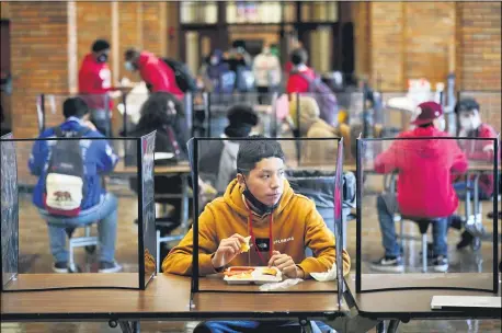  ?? AP PHOTO/CHARLIE RIEDEL, FILE ?? Freshman Hugo Bautista eats lunch separated from classmates by plastic dividers on March 31, at Wyandotte County High School in Kansas City, Kan., on the first day of in-person learning.