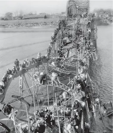  ??  ?? STATE OF WAR: Residents from Pyongyang, North Korea, and refugees from other areas crawl over shattered girders of the city’s bridge as they flee south across the Taedong River to escape Chinese Communist troops in the 1950s.