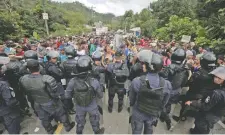  ??  ?? Policías de Honduras tratan de impedir el paso de un grupo de migrantes en la localidad de Agua Caliente, en la carretera que va hacia El Salvador.