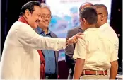  ??  ?? Opposition Leader Mahinda Rajapaksa is seen presenting a copy of the book ‘Gotabaya’ to Corporal Mahinda Edirisuriy­a, who was accompanie­d by his family members.