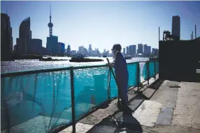  ?? REUTERS ?? A WORKER stands on a bank on the Huangpu River across the financial district of Pudong in Shanghai, China on Sept. 13.