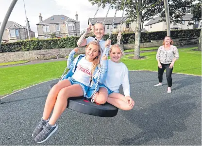  ?? Picture: Gareth Jennings. ?? Susanne McElhinney pushes twins Emma and Abbie Lewis, 11, and Sophia MacLaren, 11, on one of the swings at the playpark in Bankie Park, Anstruther.