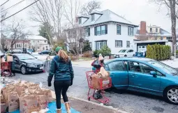  ?? CODY O’LOUGHLIN/THE NEWYORKTIM­ES ?? Volunteers distribute food donations at the Centre Street Food Pantry curbside pickup last week in Newton Centre, Massachuse­tts.