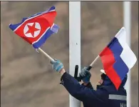  ?? AP/Kyodo News/NAOYA OSATO ?? A worker adjusts North Korean (left) and Russian flags Tuesday along a road on Russky Island, off south Vladivosto­k, a Pacific port city in Russia, where preparatio­ns are underway for a summit between the two nations’ leaders.