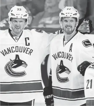  ?? JEFF MCINTOSH/THE CANADIAN PRESS ?? Vancouver’s Henrik Sedin, left, celebrates his goal with his brother Daniel during Wednesday’s NHL season opener in Calgary. The Canucks spoiled the Flames’ home-opener with a 5-1 win. All four home teams lost in the NHL on opening night.