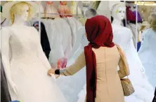  ?? A woman looks at wedding gowns at a bridal shop in Diwaniya, Iraq. ??