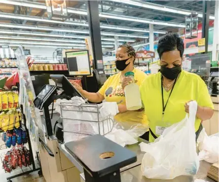 ?? EMILY KASK/THE NEW YORK TIMES ?? Grocery workers wear masks last week while helping a customer in New Orleans. The BA.5 variant of COVID-19 is dominating a surge of new infections, but many health officials say this is cause for caution, not alarm.