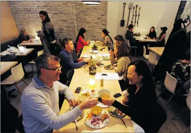  ?? STEVE BOSCH/ PNG ?? Communal tables, like this one at Heirloom Vegetarian restaurant in Vancouver, seem to be a trend among restaurant­s, daring us to shrink our definition of personal space.