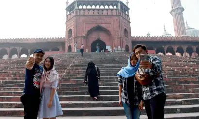  ?? — AFP ?? Tourists take selfie outside the Jama Masjid amid smog in New Delhi on Thursday.