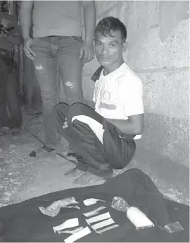  ??  ?? Evmar Vasquez sits on the ground while policemen account for the drugs seized from him during a buy-bust operation in Sitio Laguna, Barangay Basak-Pardo, Cebu City. ROWENA D. CAPISTRANO