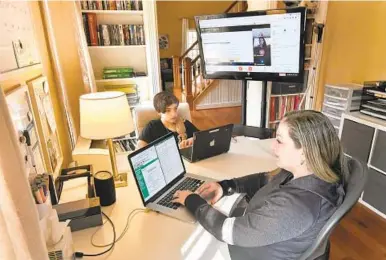  ?? AMY DAVIS/BALTIMORE SUN ?? Jenn Ambrosiano-Reedholm shares her home office with her 13-year-old son, Kyle Reedholm. A portable large TV screen, hooked up to Kyle’s laptop, allows her to monitor his online classes while she works.