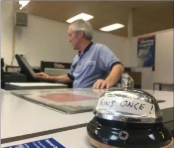  ?? KEVIN TUSTIN - DIGITAL FIRST MEDIA ?? A bell on the counter asks customers to ring it once for assistance. As the only worker in the office, Jim Gray, background, may be off attending to other tasks at the Yeadon Post Office.