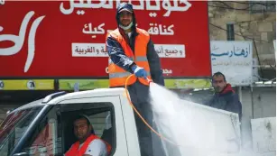  ?? (Wisam Hashlamoun/Flash90) ?? WORKERS DISINFECT a street in Hebron yesterday.