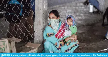  ?? — AFP ?? NEW DELHI: A woman holding a child waits with other migrant workers for transport to go to their hometowns in Uttar Pradesh and Bihar states after police stopped them from crossing the Delhi-Uttar Pradesh border on foot as the government eased a nationwide lockdown as a preventive measure against the COVID-19 coronaviru­s.