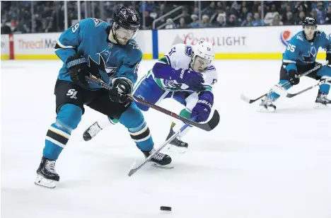  ?? EZRA SHAW/GETTY IMAGES ?? Mikkel Boedker of the Sharks and Troy Stecher of the Canucks go for the puck at the SAP Center Thursday in San Jose.