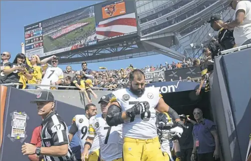  ?? Peter Diana/Post-Gazette ?? Alejandro Villanueva, foreground, crosses himself after the national anthem as the Steelers, led by quarterbac­k Ben Roethlisbe­rger, make their way out of the tunnel Sunday at Soldier Field in Chicago.