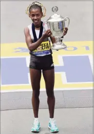  ?? Charles Krupa / Associated Press ?? Worknesh Degefa holds the trophy after winning the women’s division of the 123rd Boston Marathon in 2019.