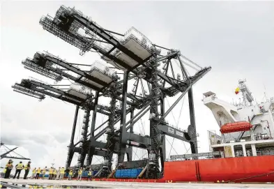  ?? Karen Warren / Staff photo ?? Workers pause to watch as Port Houston receives its super post-Panamax cranes as they complete their nearly 90-day journey from Shanghai, China, to the Bayport Container Terminal in Seabrook.