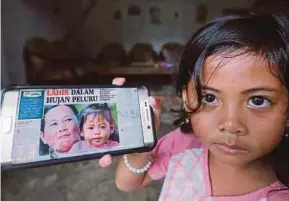  ??  ?? Farhana Rashidi, who is known as ‘Puteri Daulat’, showing a digital version of a newspaper story about her birth during the Lahad Datu intrusion.