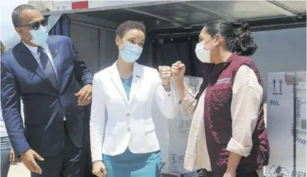  ?? (Photos: Garfield Robinson) ?? Senator Kamina Johnson Smith (centre), minister of foreign affairs and foreign trade, fist bumps Laura Elena, executive director of Mexican internatio­nal cooperatio­n agency Amexcid, after receiving 65,000 doses of the Astrazenec­a vaccine yesterday from Mexico. Dr Christophe­r Tufton, minister of health and wellness, looks on.