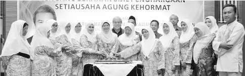  ??  ?? Dayang Morliah (seventh left) cuts a celebrator­y cake with her committee members. Awang Tengah is behind her.