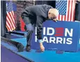  ?? ?? Joe Biden bends to pick up a badge at a presidenti­al rally in Georgia