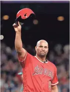  ??  ?? Angels slugger Albert Pujols waves his helmet to fans after hitting a single against the Mariners for the 3,000th of his career. ELAINE THOMPSON/AP